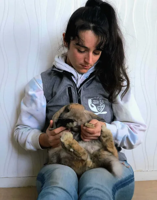 Ostéopathe animalier tenant un chiot sur ses genoux pendant une consultation à domicile