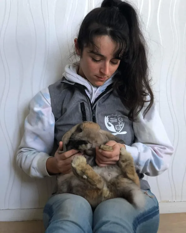 Lapin tenu contre sa praticienne pendant une séance d'ostéopathie pour NAC